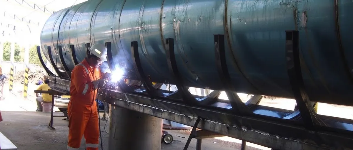 Soldador trabajando en un tanque de acero en el taller