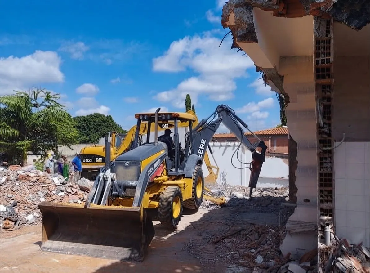 Backhoe loader with a breaker demolishing a structure
