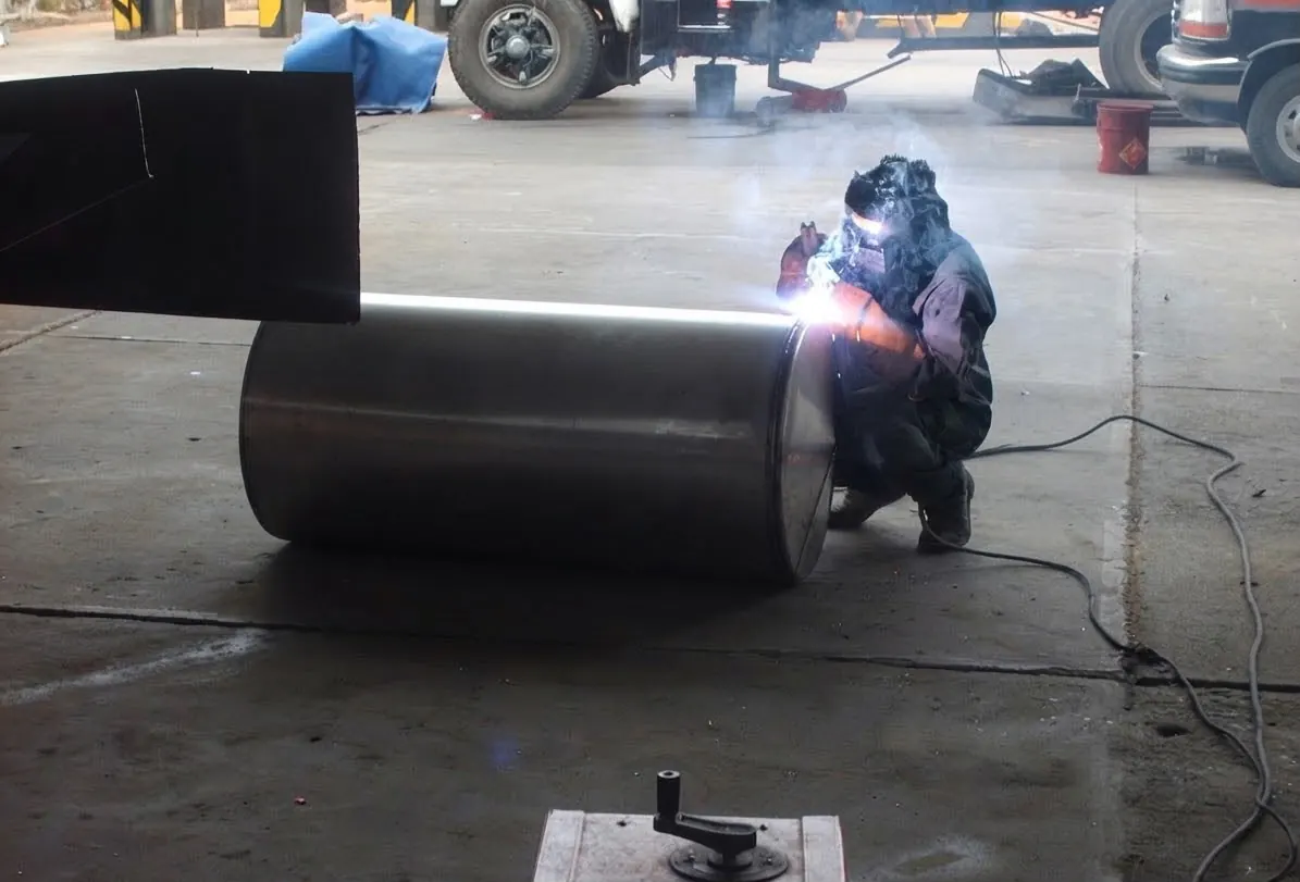 Welder working on the shell of a steel tank