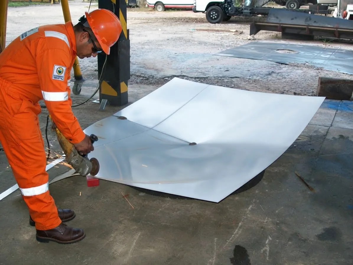 Worker grinding a steel sheet for a tank